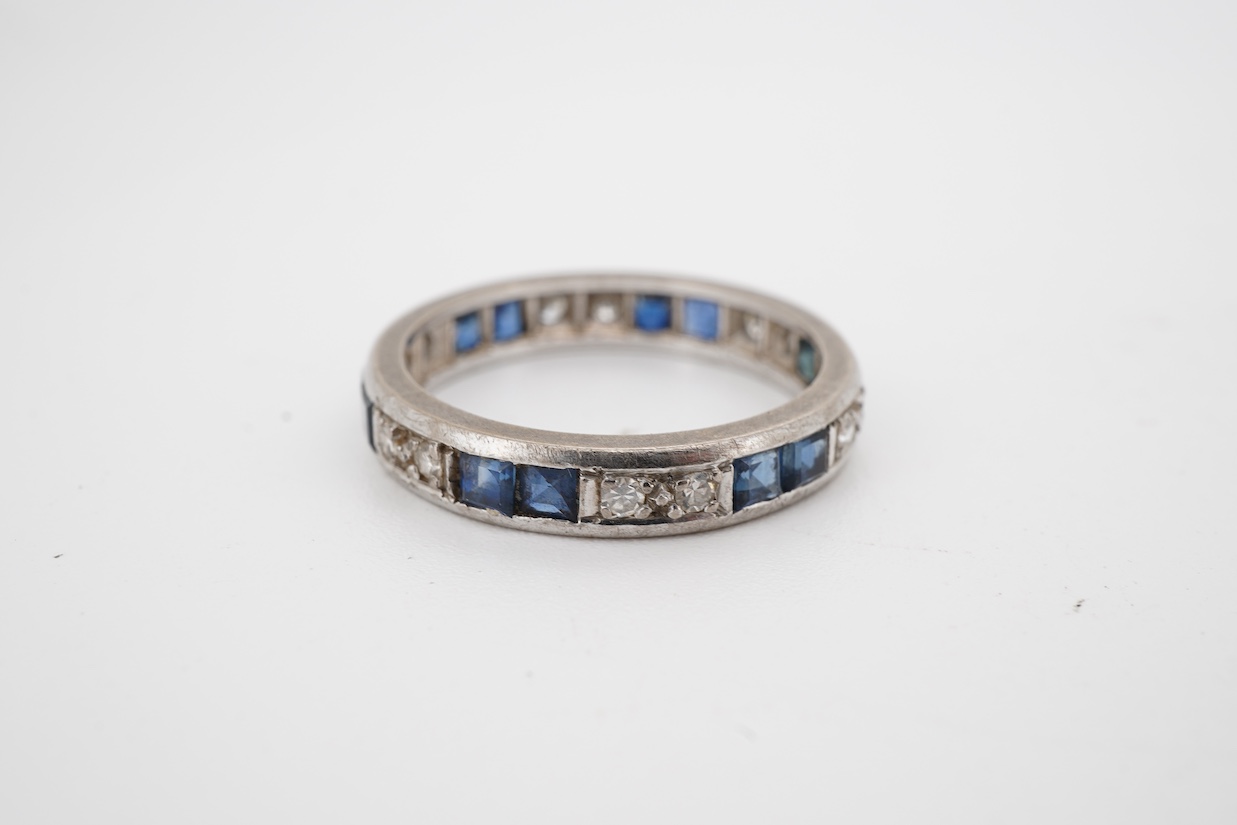 A white metal, twelve stone diamond and twelve stone sapphire set full eternity ring, size N, (remnants of an 18ct hallmark?).